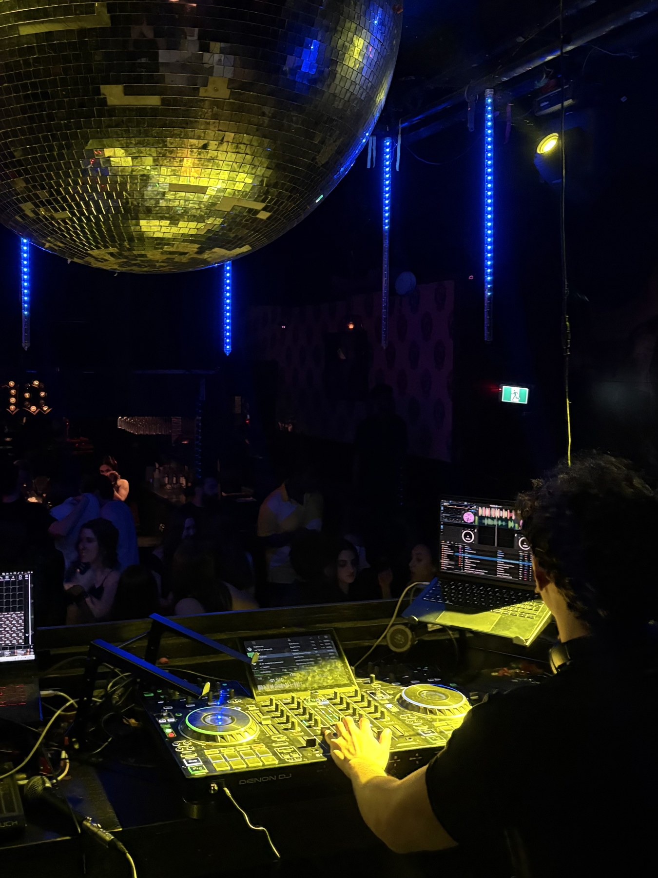 Crowd and DJ booth beneath a disco ball