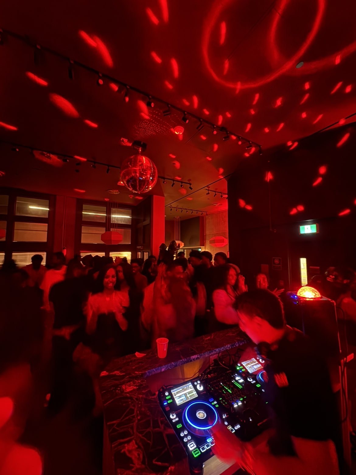 Red-lit dance floor seen from the DJ booth