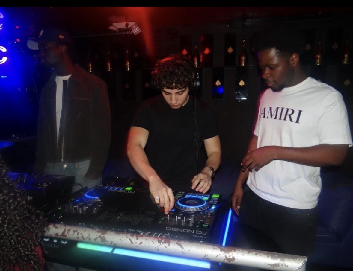 DJ mixing with a guest beside the booth